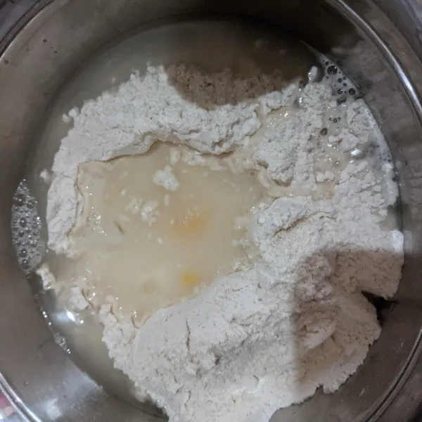 Masukkan tepung, ragi, susu, gula. Aduk merata. Lalu buat cekungan ditengah. Beri telur kuning dan air. Mix dengan tangan atau spatula cukup hingga homogen merata dan lengket.