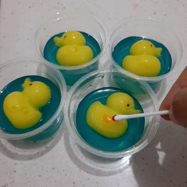Keluarkan puding bebek dari cetakan. Hias mata, paruh dan sayap. Tambahkan lagi sisa adonan biru atau langsung disajikan.