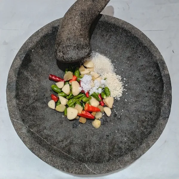 Dalam cobek, masukan bawang putih, kencur, cabe, garam, kaldu jamur, gula pasir. Ulek kasar.