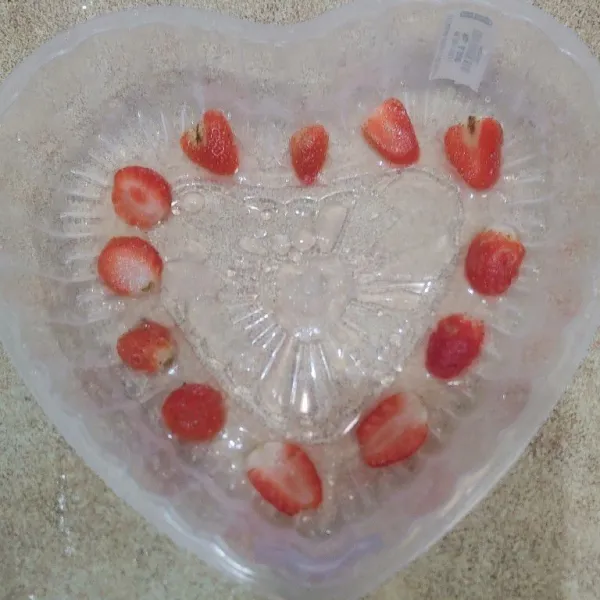 Siapkan cetakan bentuk love, tata irisan buah strawberry lalu tuang sedikit demi sedikit puding strawberry. Tunggu sampai puding set.
