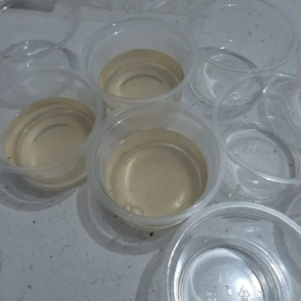 Masukkan cairan puding ke dalam cup. Sisakan sedikit untuk lem