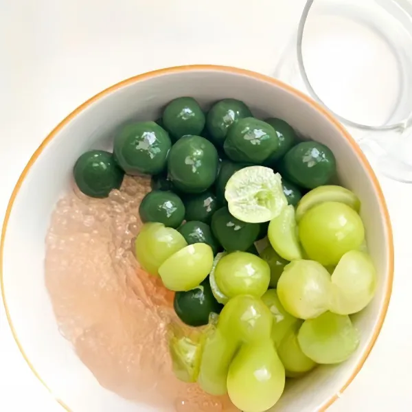 Taruh sagu mutiara dan adonan bulat di wadah. Tambahkan buah anggur hijau yang sudah di potong