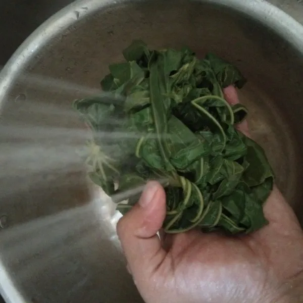 Matikan api lalu tiriskan air, setelah itu bilas daun singkong dengan air baru