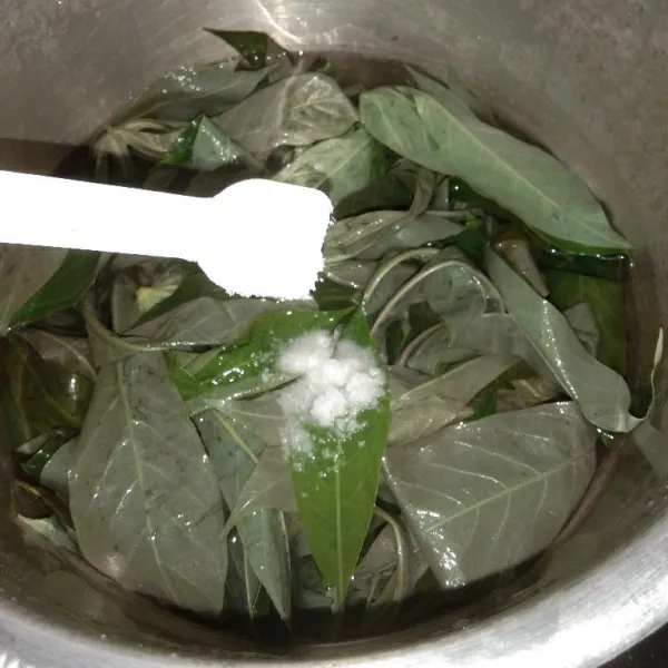Rendam daun singkong dalam panci, beri 1 sendok teh garam lalu rebus kurang lebih 10 menit