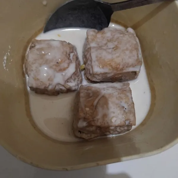 Buat larutan tepungnya. Jangan sampai encer dan jangan terlalu kental. Celupkan tahu pada adonan hingga rata.