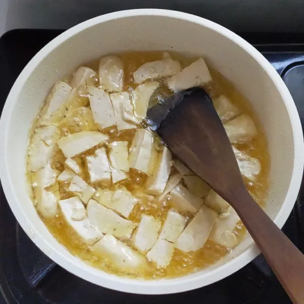 Panaskan minyak, kemudian goreng tahu putih hingga kuning kecokelatan, lalu angkat dan tiriskan.