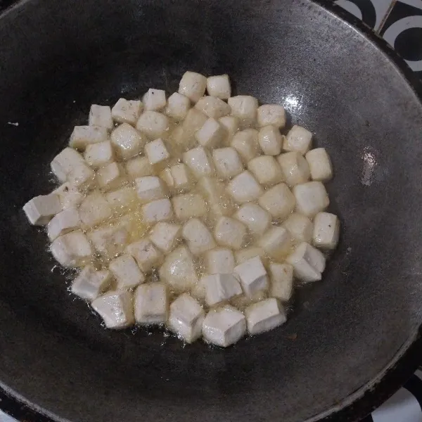 Goreng tahu yang sudah di potong dadu sampai setengah matang