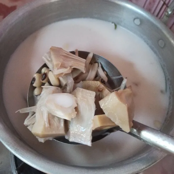 Tiriskan tewel dan kacang Tolo yang sudah matang, kemudian pindahkan kedalam panci yang berisi santan.