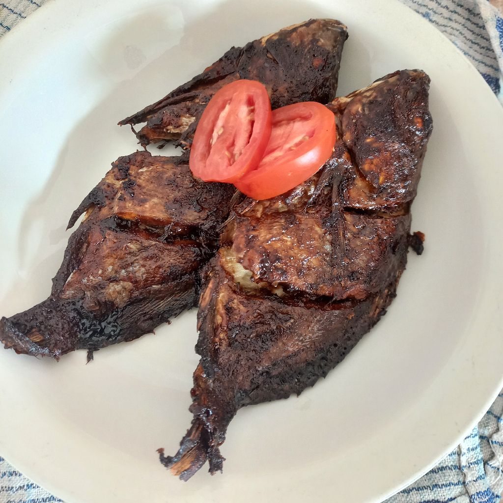 Proses memasak kuah pliek u ikan mujair di dalam panci dengan api kecil