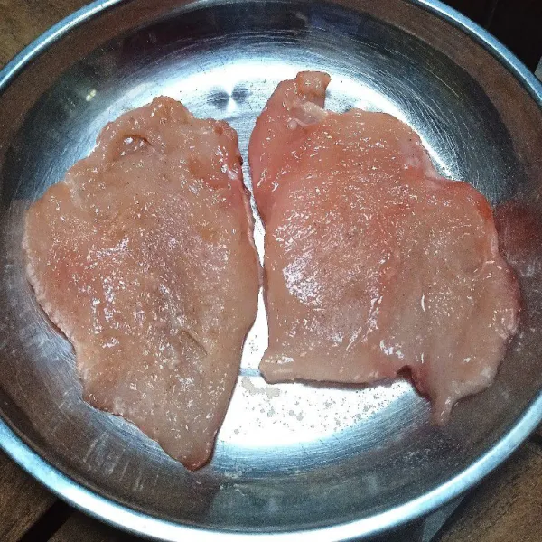 Pukul-pukul dada ayam dengan pemukul daging, kemudian taburi dengan bawang putih bubuk, garam,dan lada bubuk di kedua sisinya. Simpan dalam kulkas selama 30 menit.