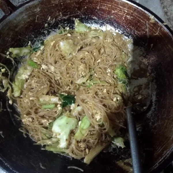 Tambahkan orak arik telur dan aduk rata kembali. Masak hingga air set, dan warna bihun sudah cantik