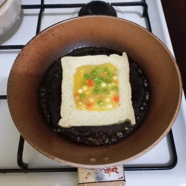 Tuang kocokan telur secukupnya pada bagian tengah roti.