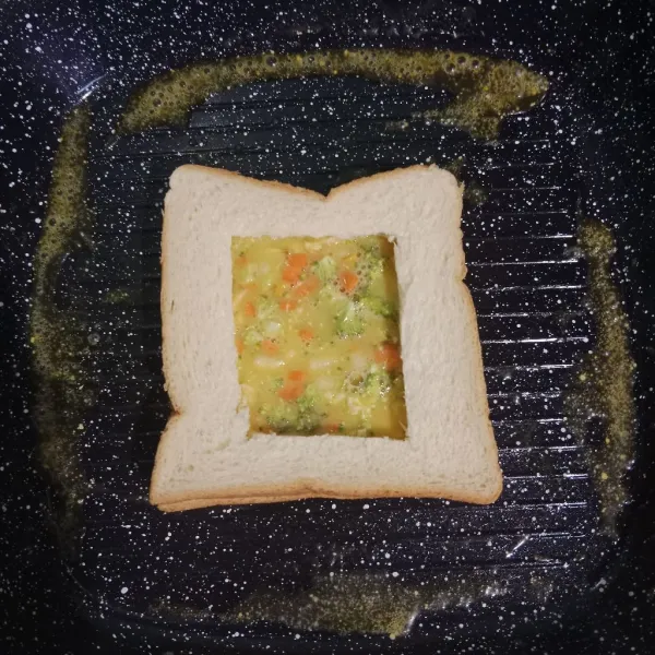 Panaskan pan, masukkan margarin bertahap. Letakkan 2  roti tawar, masukkan kocokan telur pada lubang.