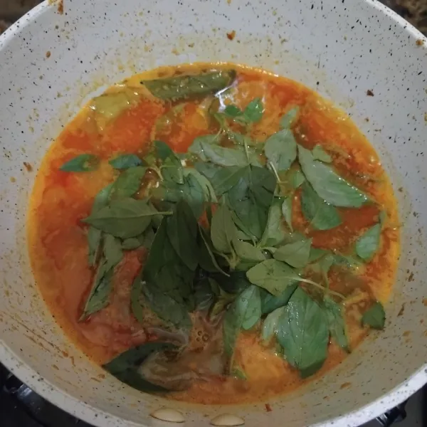Beri daun kemangi dan bumbu perasa, lalu aduk sampai rata dan biarkan mendidih. Tata ikan di piring, lalu beri kuahnya.