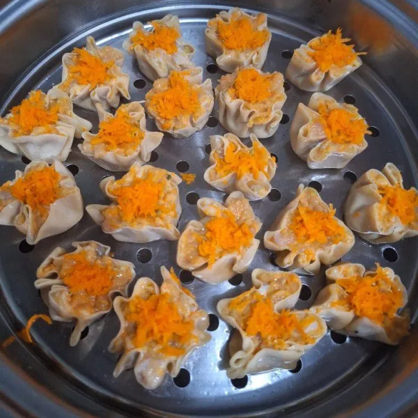 Ambil kulit dimsum, oleskan isian ayam dipermukaannya. Bentuk dan agak ditekan agar membulat. Kukus hingga matang.