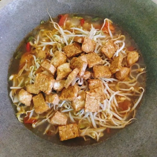 Masukkan tahu dan tempe yang sudah digoreng ke dalam wajan, aduk rata dengan bumbu.