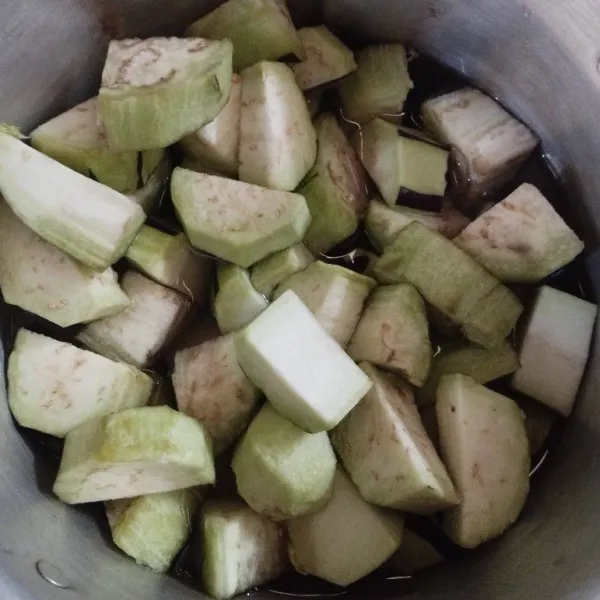 Kupas terong, lalu rendam di air agar tidak berubah warna hitam