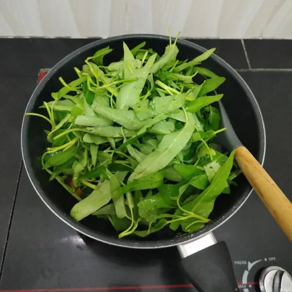 Masukkan kangkung, aduk rata. Masak hingga kangkung setengah layu.