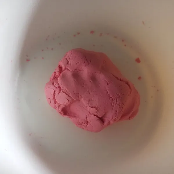 Campur tepung ketan, tepung beras, garam dan pewarna merah jadi satu tuang air hangat sedikit demi sedikit uleni sampai adonan tercampur rata dan bisa dibentuk.