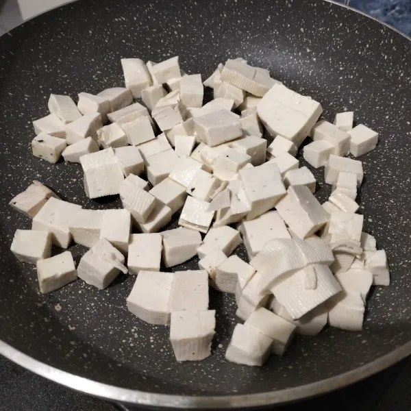 Oles permukaan wajan datar dengan minyak zaitun. Kemudian masukkan tahu. Bolak balik tahunya sampai kedua sisi kuning keemasan. Angkat, sisihkan.