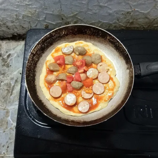 Masukkan margarin, kemudian oleskan saus sambal di adonan pizza hingga rata. Masukkan bakso sapi dan sosis ayam yang sudah di masak tadi dan merica bubuk. Tambahkan tomat dan irisan cabai rawit juga.