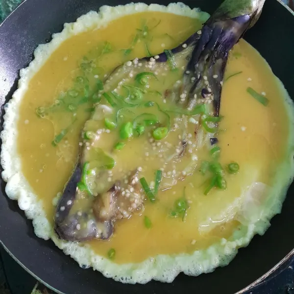 Lalu letakkan terong, siram kembali dengan telur balikan sampai ke dua sisi matang