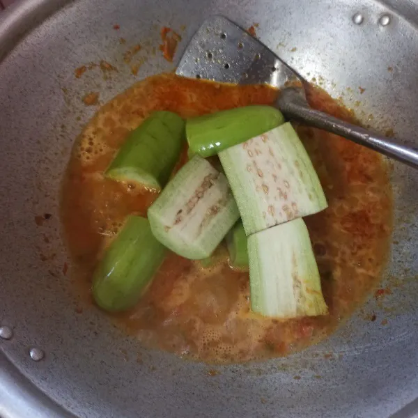 Setelah bumbu matang tambahkan air secukupnya, masukkan terong dan daun bawang ungkep sebentar hingga layu.