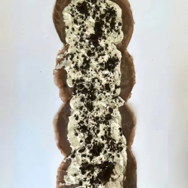 Oleskan krim kocok pada permukaan kue yang sudah matang, taburi dengan Oreo yang sudah dihancurkan