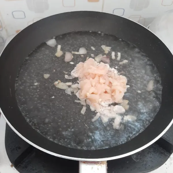 Tumis bawang putih dan bawang merah sampai harum. Tambahkan air lalu masukkan daging ayam