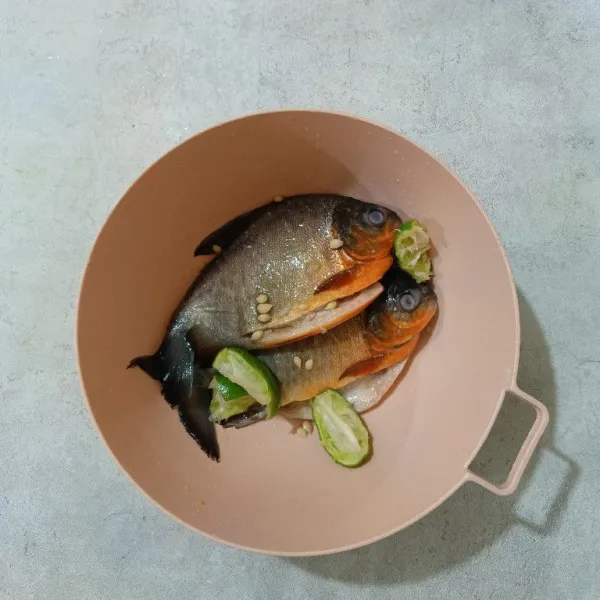 Cuci bersih ikan, lalu lumuri ikan dengan air perasan jeruk nipis. Diamkan selama 10 menit, kemudian bilas hingga bersih. Sisihkan.