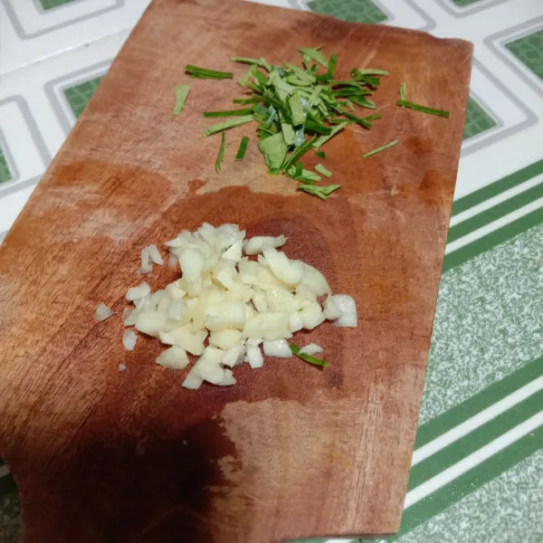 Iris daun jeruk dan bawang putih yang sudah dicuci bersih.