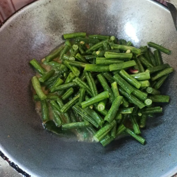 Setelah bumbu matang tambahkan air secukupnya kemudian masukkan kacang panjang aduk rata dan masak hingga setengah matang.