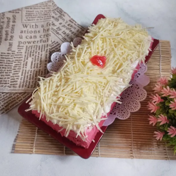 Setelah matang keluarkan dari loyang, dinginkan kemudian olesi dengan butter cream dan taburi dengan keju parut.