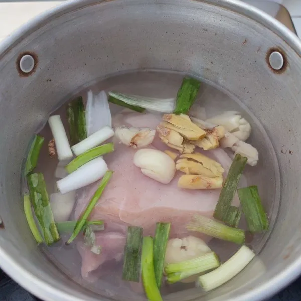 Pindahkan ke panci, tambahkan bawang putih dan jahe geprek, potongan daun bawang, dan air. Rebus hingga mendidih.