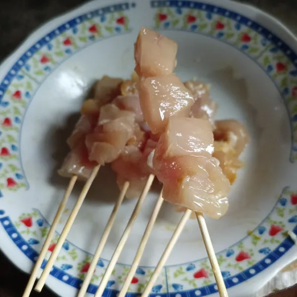 Tusuk daging ayam menggunakan tusukan sate.