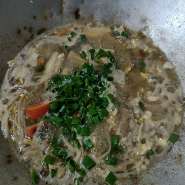 Setelah mendidih, masukkan jamur enoki. Tambahkan saus tiram, garam, gula, kaldu jamur, dan air asam. Setelah matang, masukkan tomat dan daun bawang kemudian aduk-aduk.
