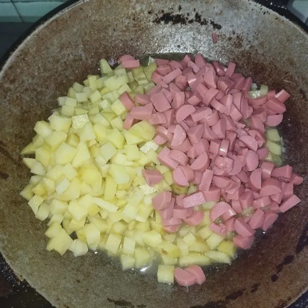 Tambahkan air, lalu masukan kentang dan sosis. Aduk rata.