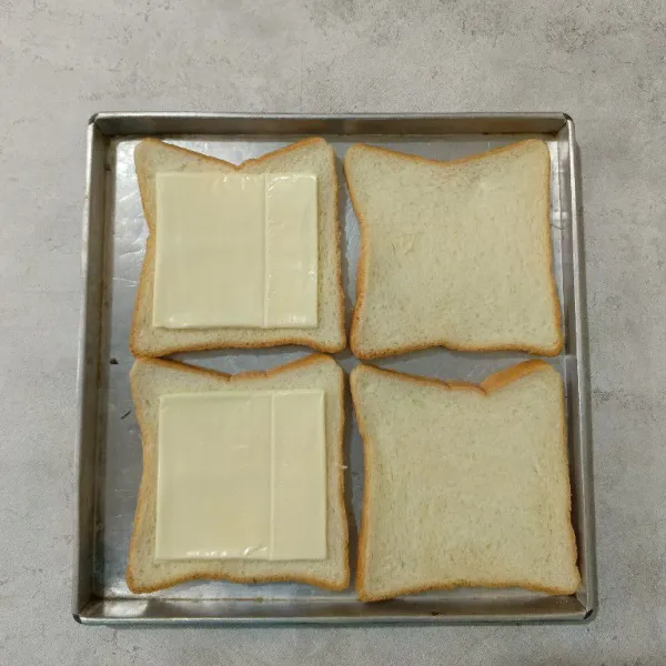 Tata roti tawar diatas loyang. Kemudian letakkan keju slice pada salah satu roti.