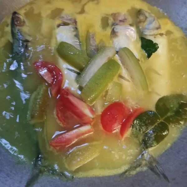 Masukkan ikan, tunggu setengah matang lalu masukkan tomat, belimbing wuluh, garam dan penyedap rasa, aduk rata.