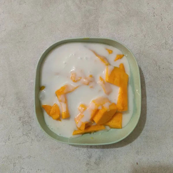 Tuang bahan saus ke dalam potongan mangga. Aduk rata.