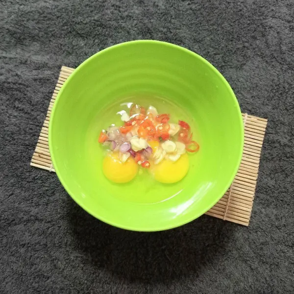 Masukkan telur dan irisan cabai rawit, bawang merah, dan bawang putih.
