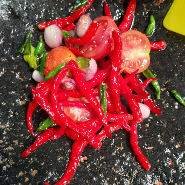 Masukan ke dalam batu penggilingan cabe, Giling halus semua bahan Sambal yang sudah di goreng tambahkan garam, kaldu bubuk dan gula merah