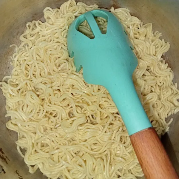 Rebus air hingga mendidih lalu masukkan minyak dan rebus mie hingga setengah matang tiriskan.