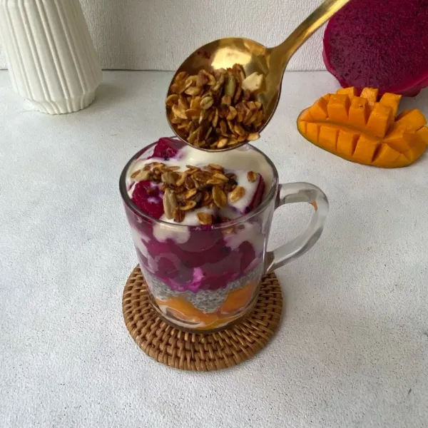 Tambahkan granola untuk lapisan paling atas. Hias dengan potongan buah naga, mangga, dan daun mint. Sajikan! Jika suka dingin, bisa disimpan ke dalam kulkas sebelum disajikan.