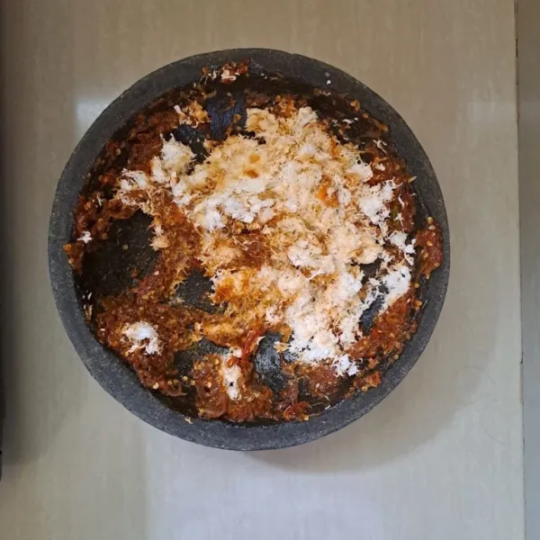 Lalu haluskan 15 buah cabai rawit merah, 5 siung bawang merah, dan 100 gram kelapa parut yang sudah dikukus terlebih dahulu