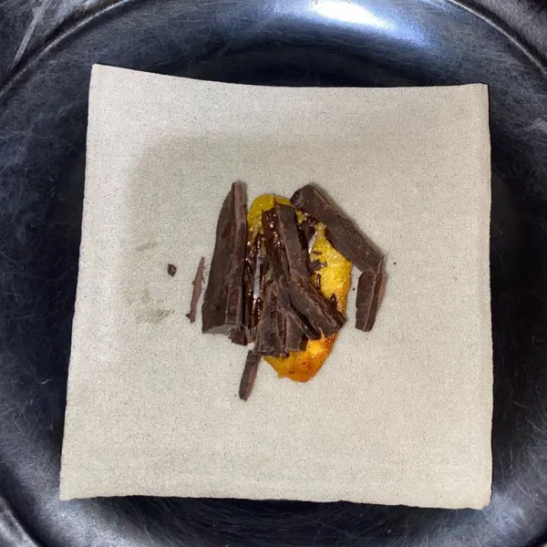 Tiap bolen ada 2 kulit pangsit ya,jadi ini kulit pangsit yang pertama diletakkan pisang yang sudah dimasak dengan margarin tadi,dan letak coklat batang diatasnya,lalu lipat rapi menggunakan olesan air