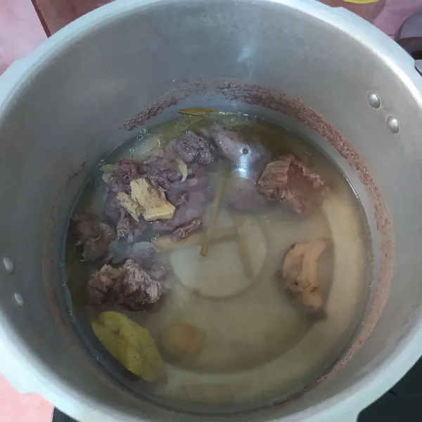 Presto daging bersama daun salam, serai, dan lengkuas selama 30 menit.