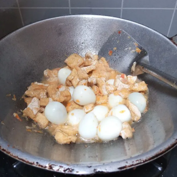 Tuang sedikit air. Masukkan tahu dan telur puyuh. Aduk.