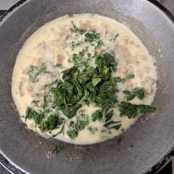 Masukkan daun singkong yang sudah dipotong kecil lalu aduj hingga matang.