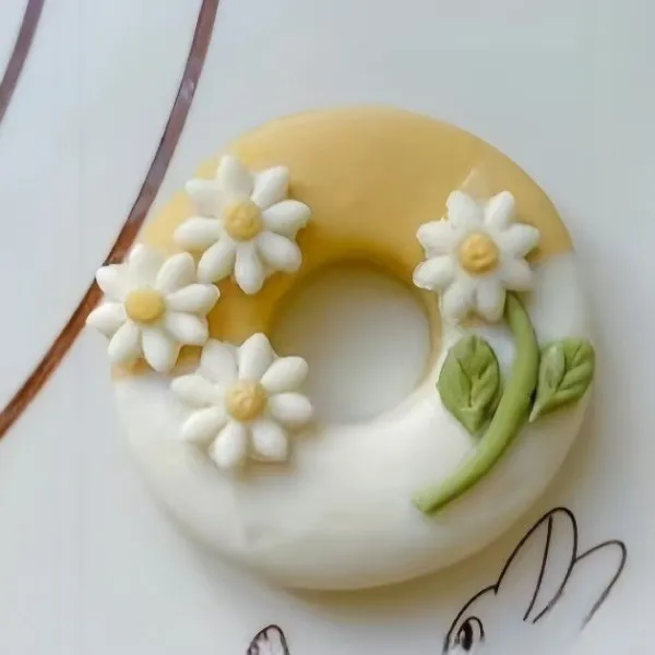 Oleskan permukaan donat dengan air, lalu tempelkan hiasan berbentuk bunga dan daun